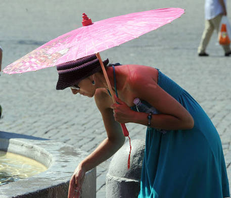 Una ragazza si rinfresca con l'acqua di una fontana (archivio) © ANSA